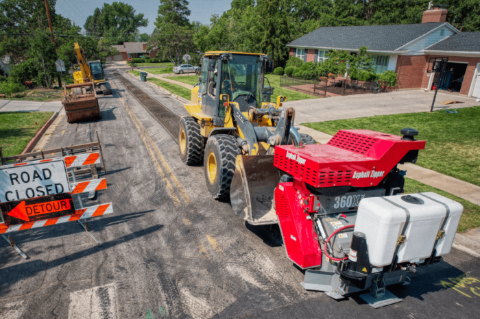 Asphalt grinder pulverizes asphalt for utility trenching project.